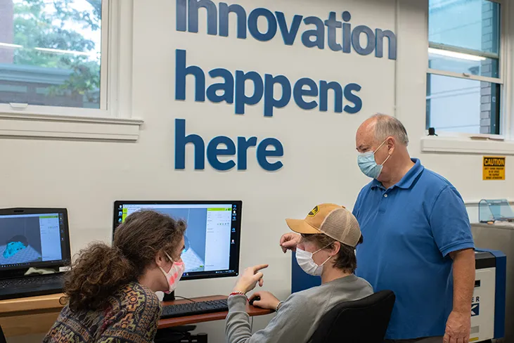 Two students get help from a mentor while working on an innovation project