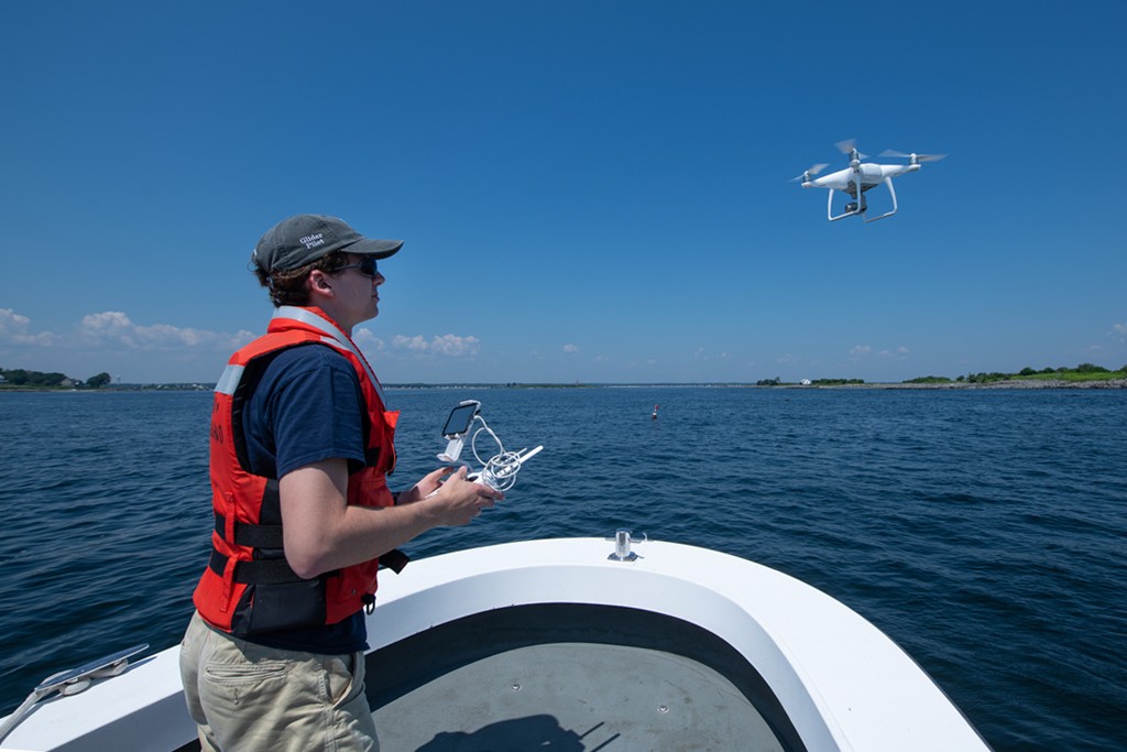 A student in a boat flying a drone over the water