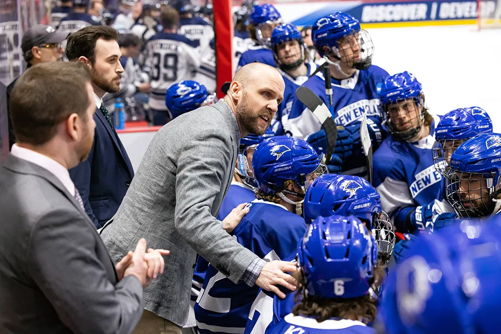 Hockey coach speaking to the U N E hockey team during a game