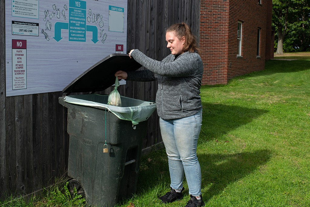 A student placing compost into a compost dropoff bin