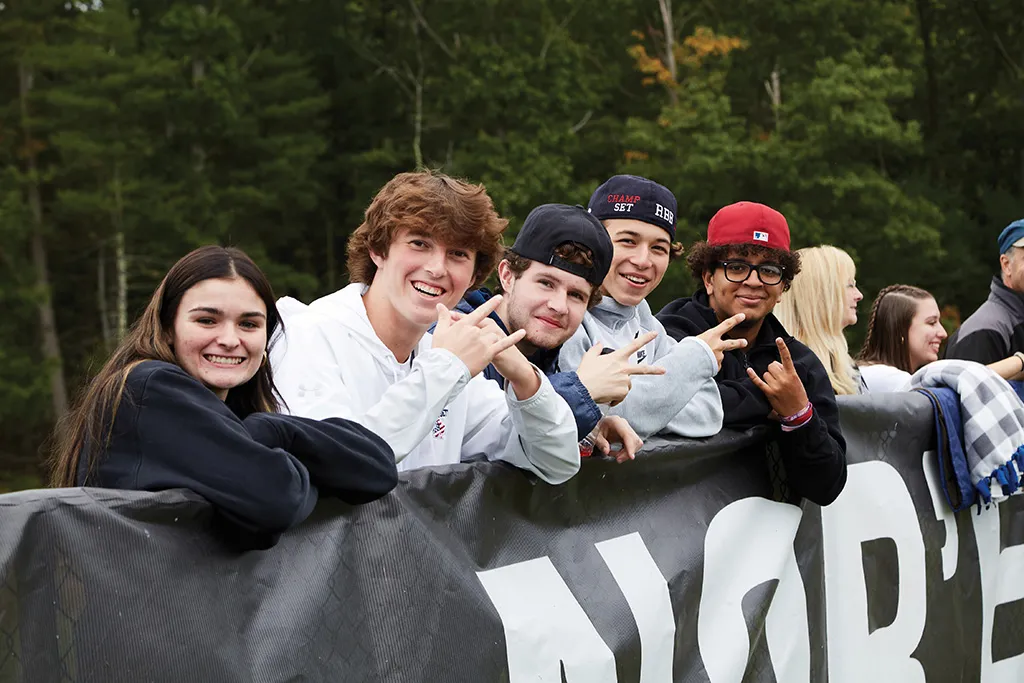 Five U N E students smile and pose for the camera at a Homecoming event