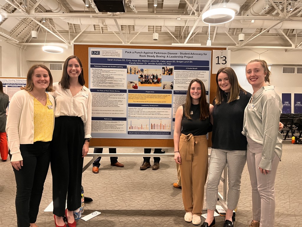 Celia Larson (second from left) and her group pose in front of their research poster.