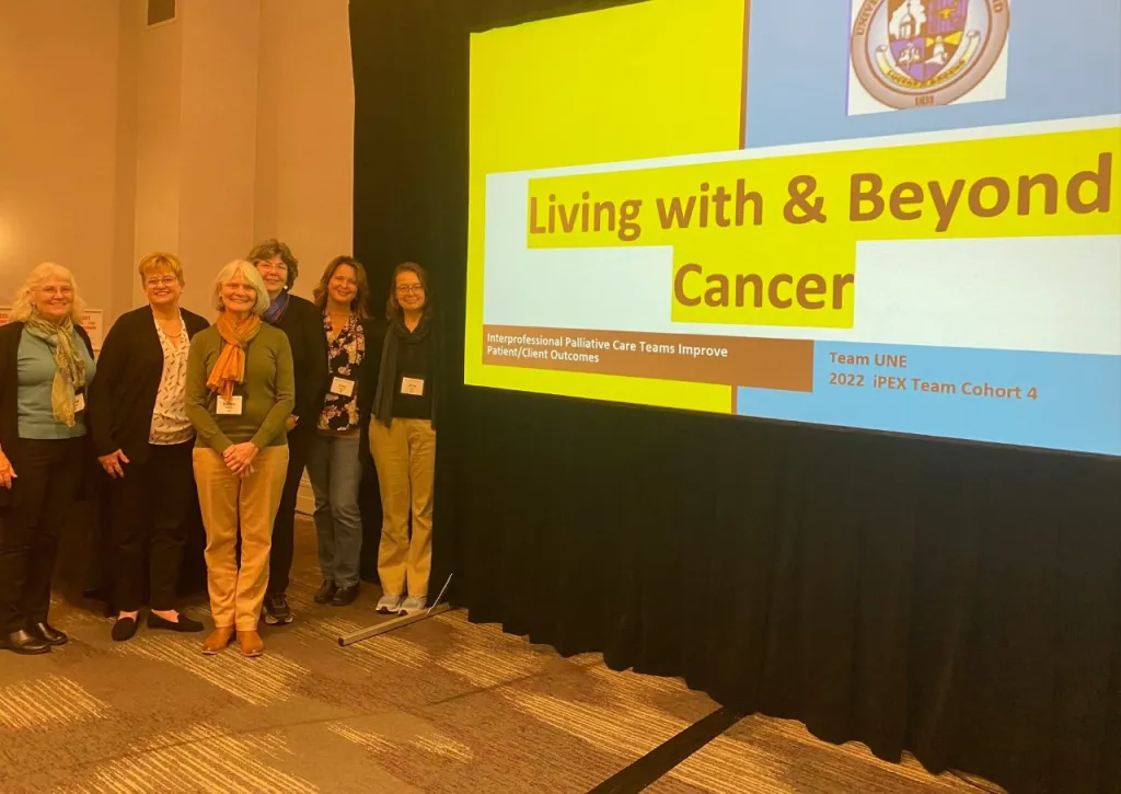 UNE health professions faculty pose in front of their presentation "Living with and beyond cancer"