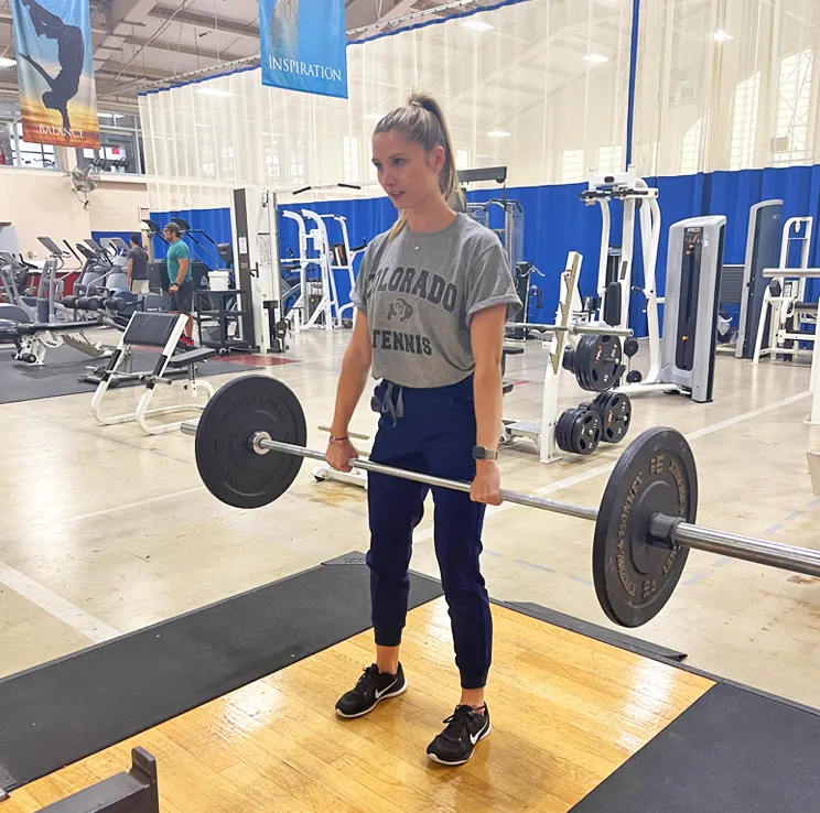 A student performing a Romanian deadlift with a barbell