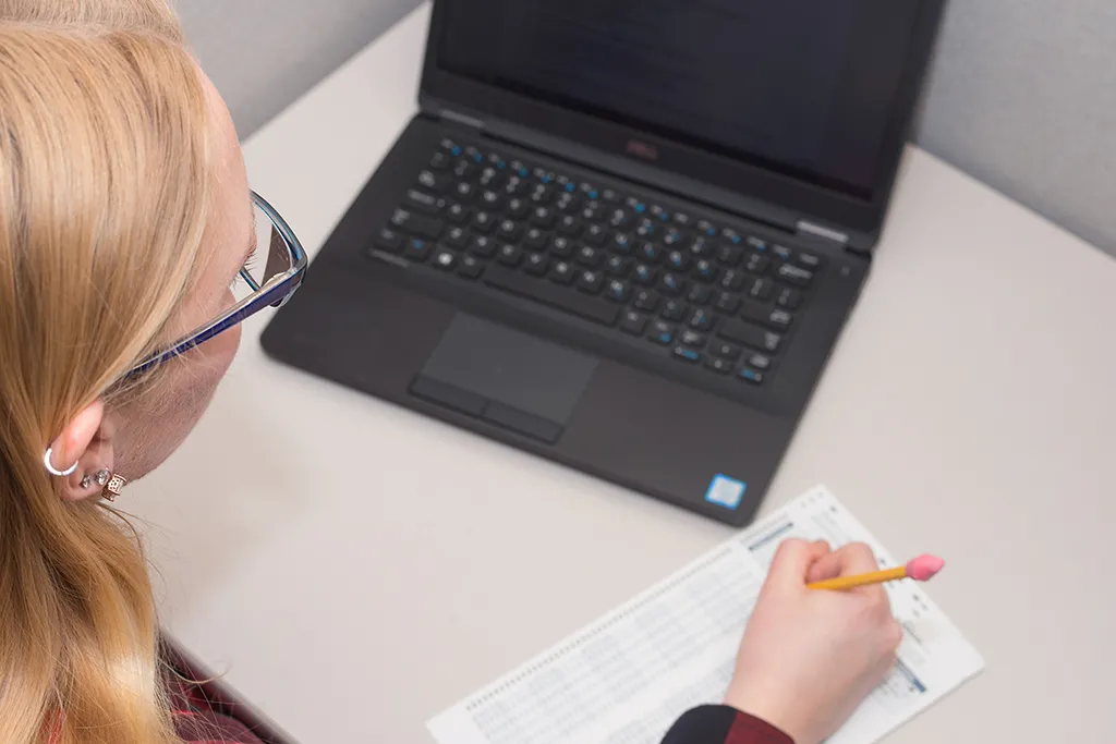 A student looks at a laptop as they fill out a multiple-choice test