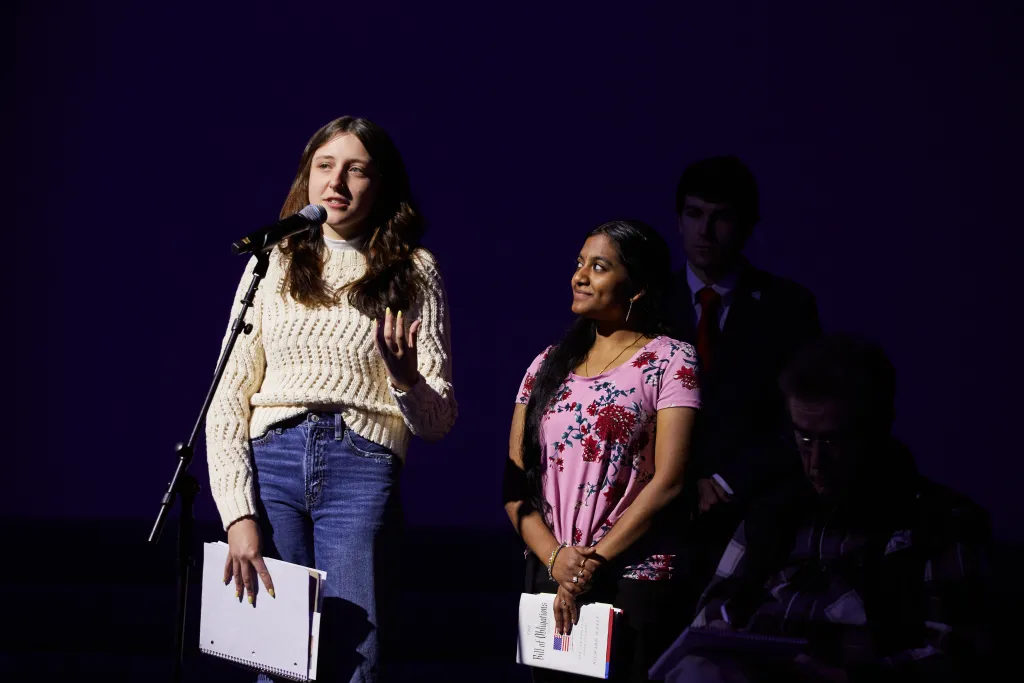 Two female students stand at a microphone to ask questions for the speaker