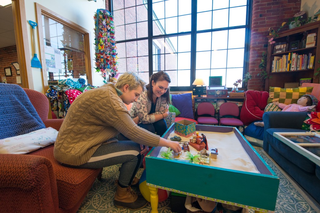 A U N E student works with a student at a sensory table at the Dempsey Center