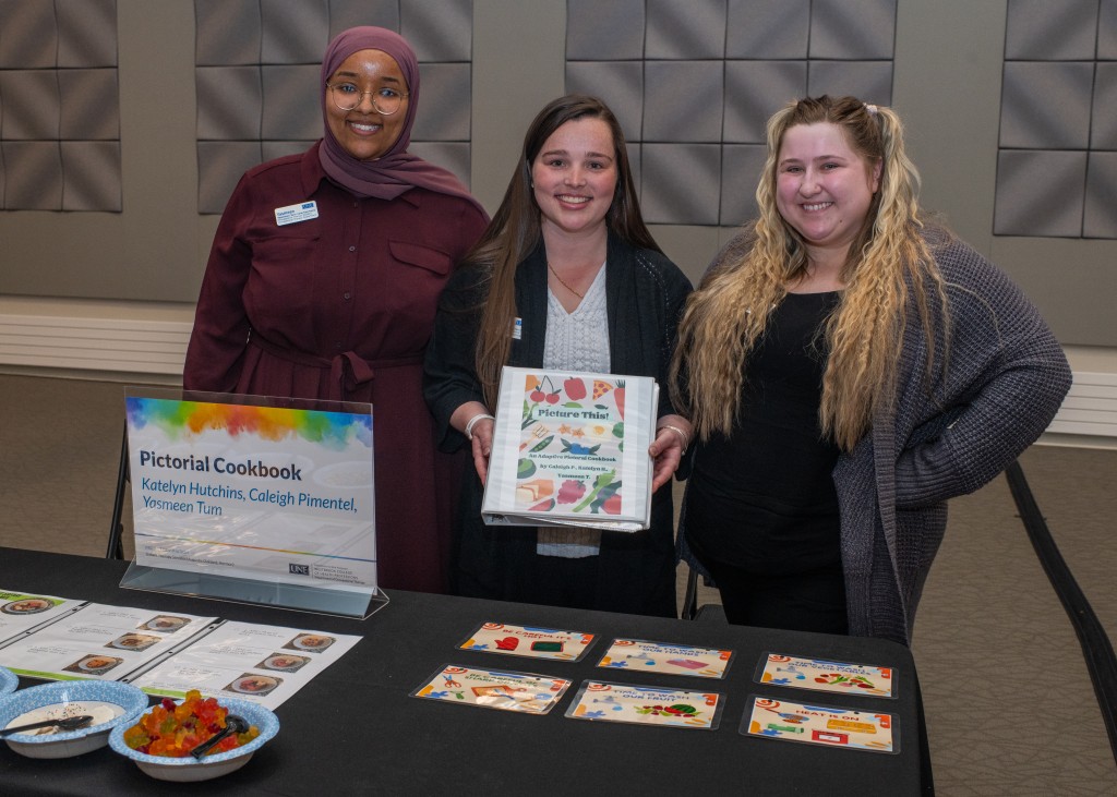 Three female students showcase the pictorial cookbook they designed