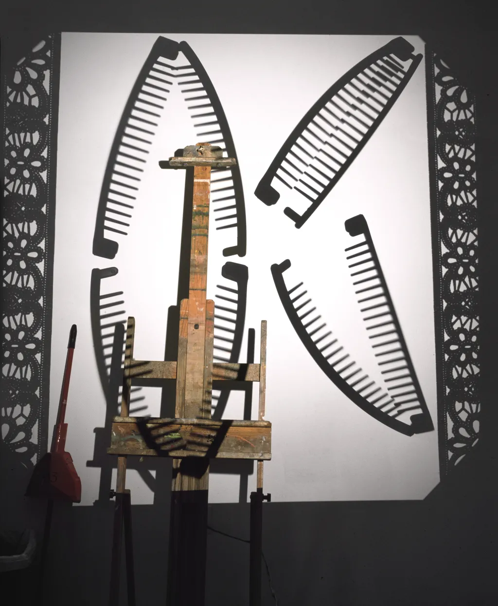 A broom and easel are photographed against a bright background with combs displayed