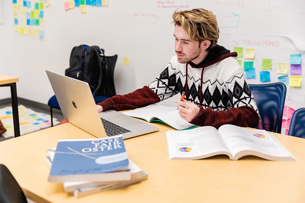 A student studying with their laptop and several books
