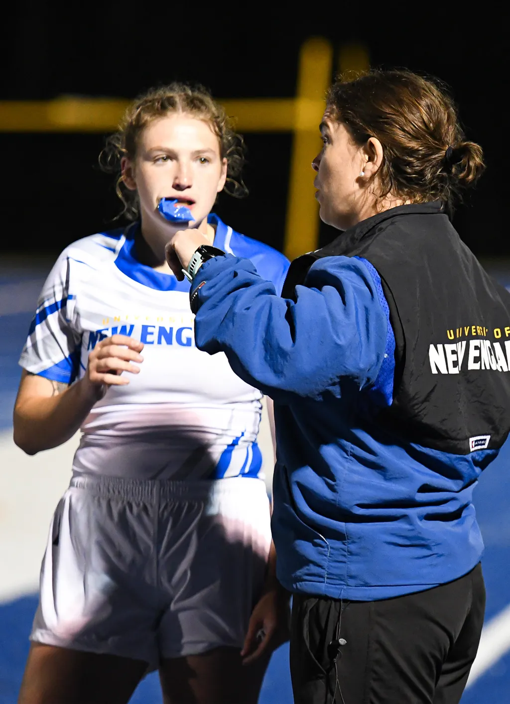 A coach speaks with a field hockey player during a game