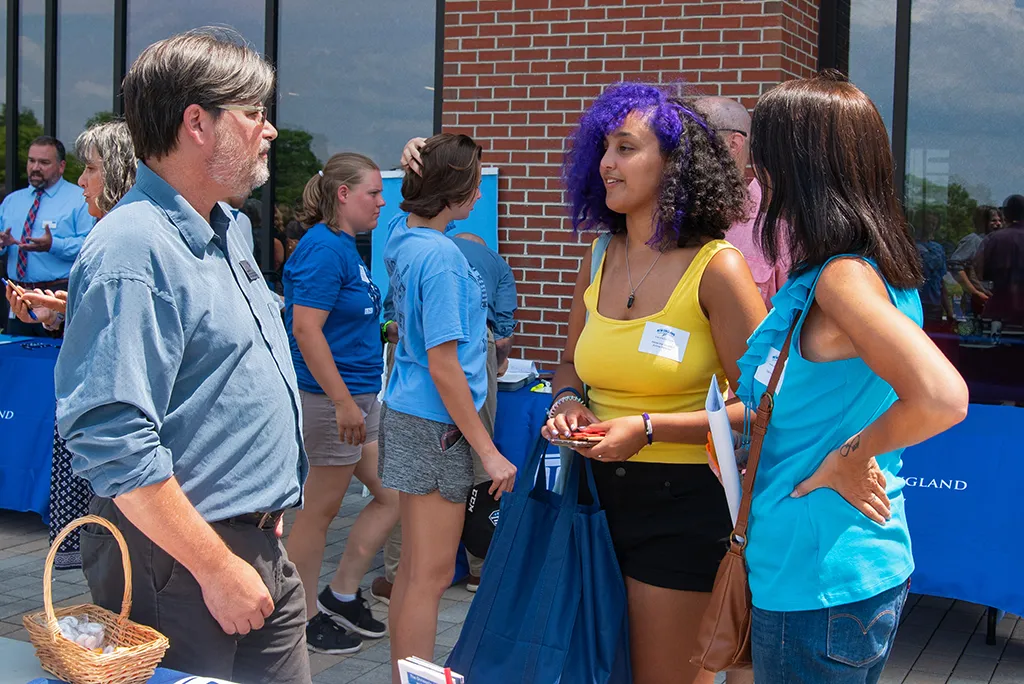 A group of students speak with a faculty member at orientation