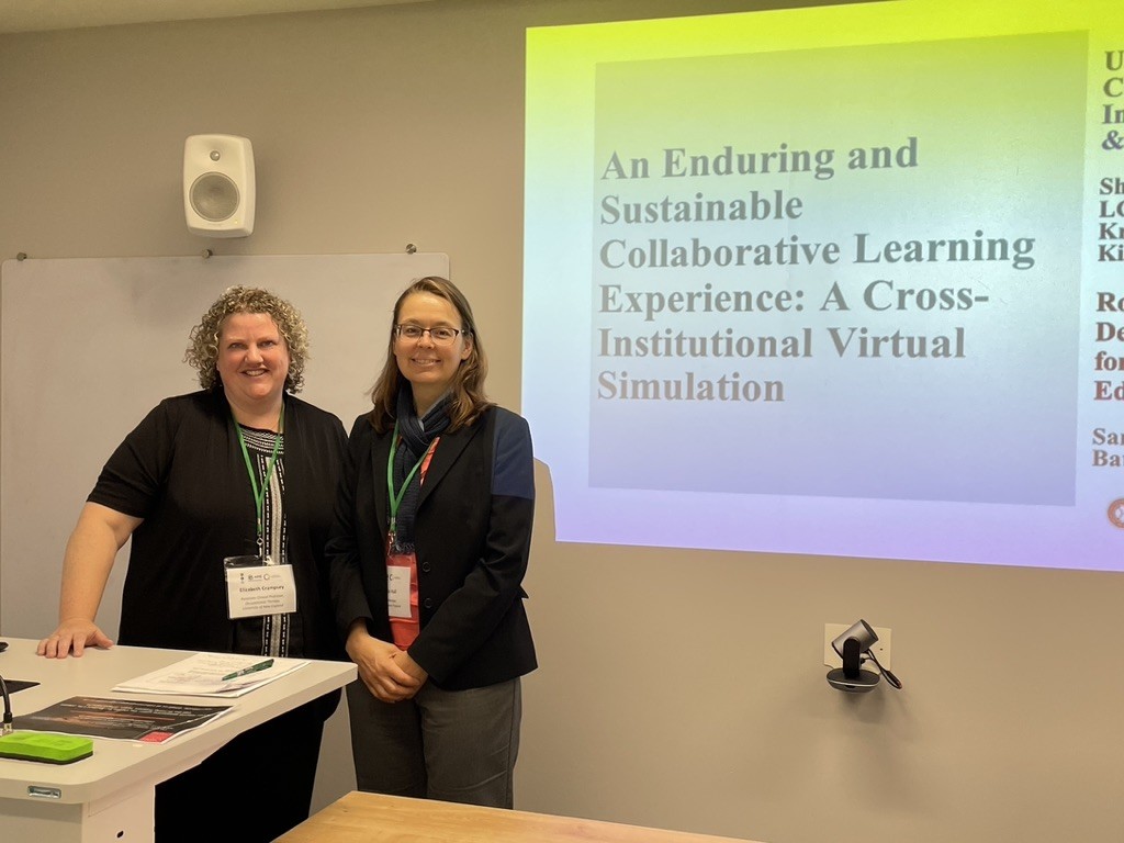 Elizabeth Crampsey and Kris Hall stand in front of powerpoint slide