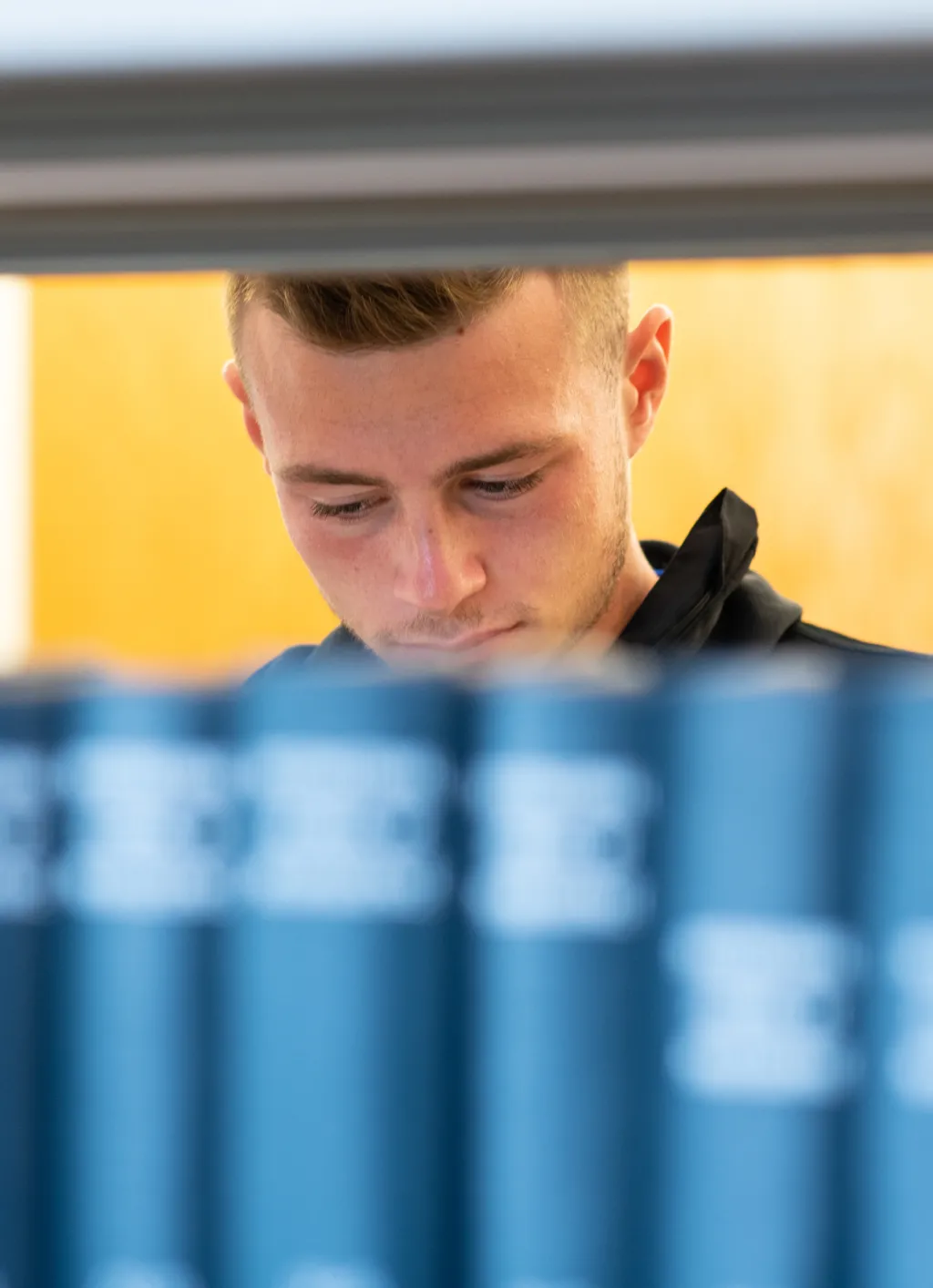 A student stands behind a row of books in the Ketchum Library