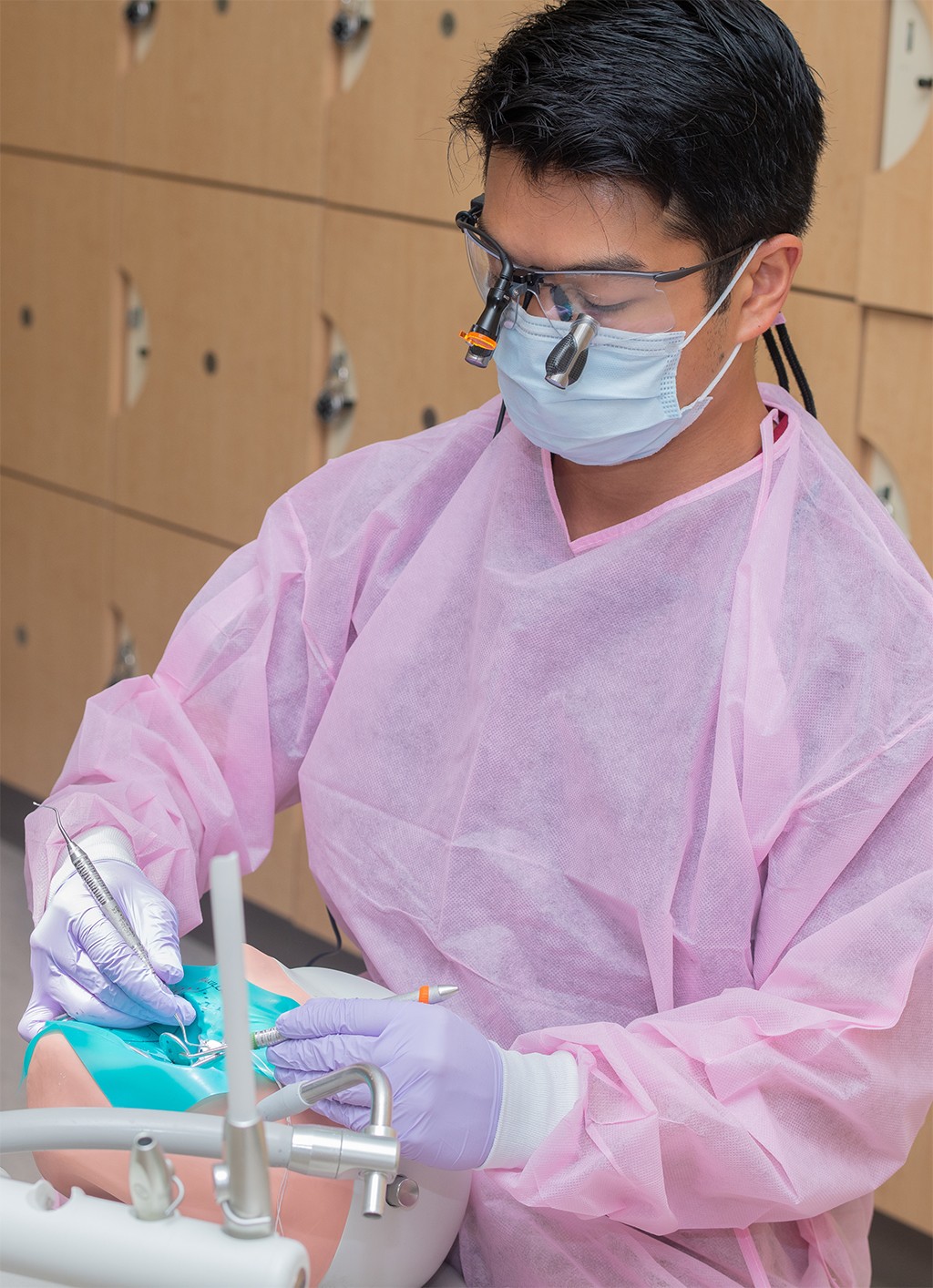 A dental medicince student wearing pink scrubs practicing skills in the Oral Health Center