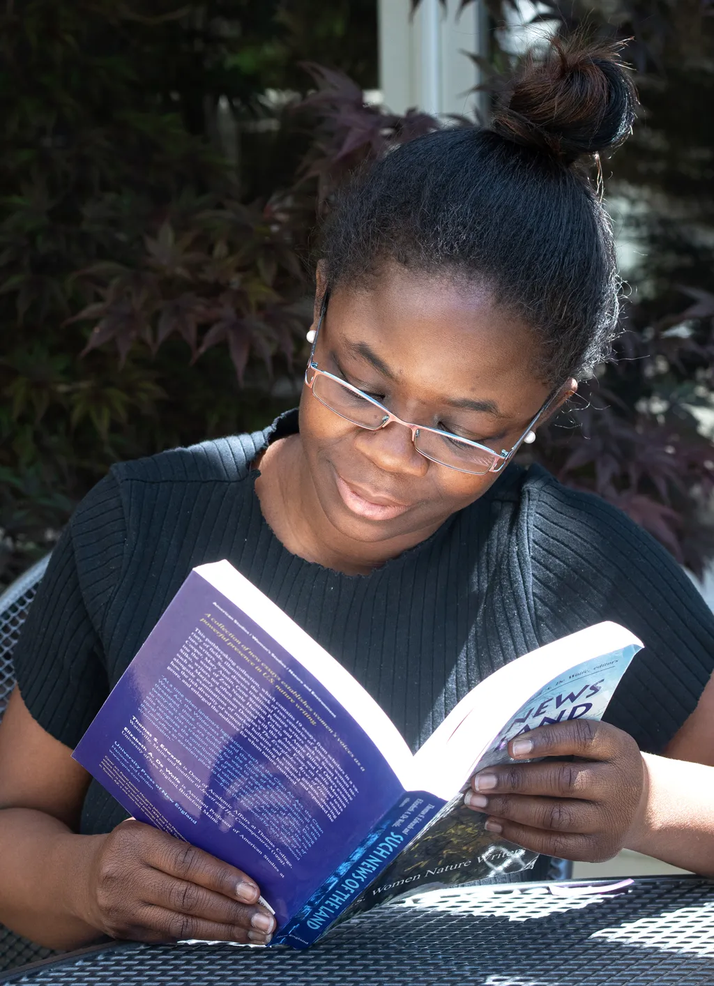 A student sitting outside and reading a class book