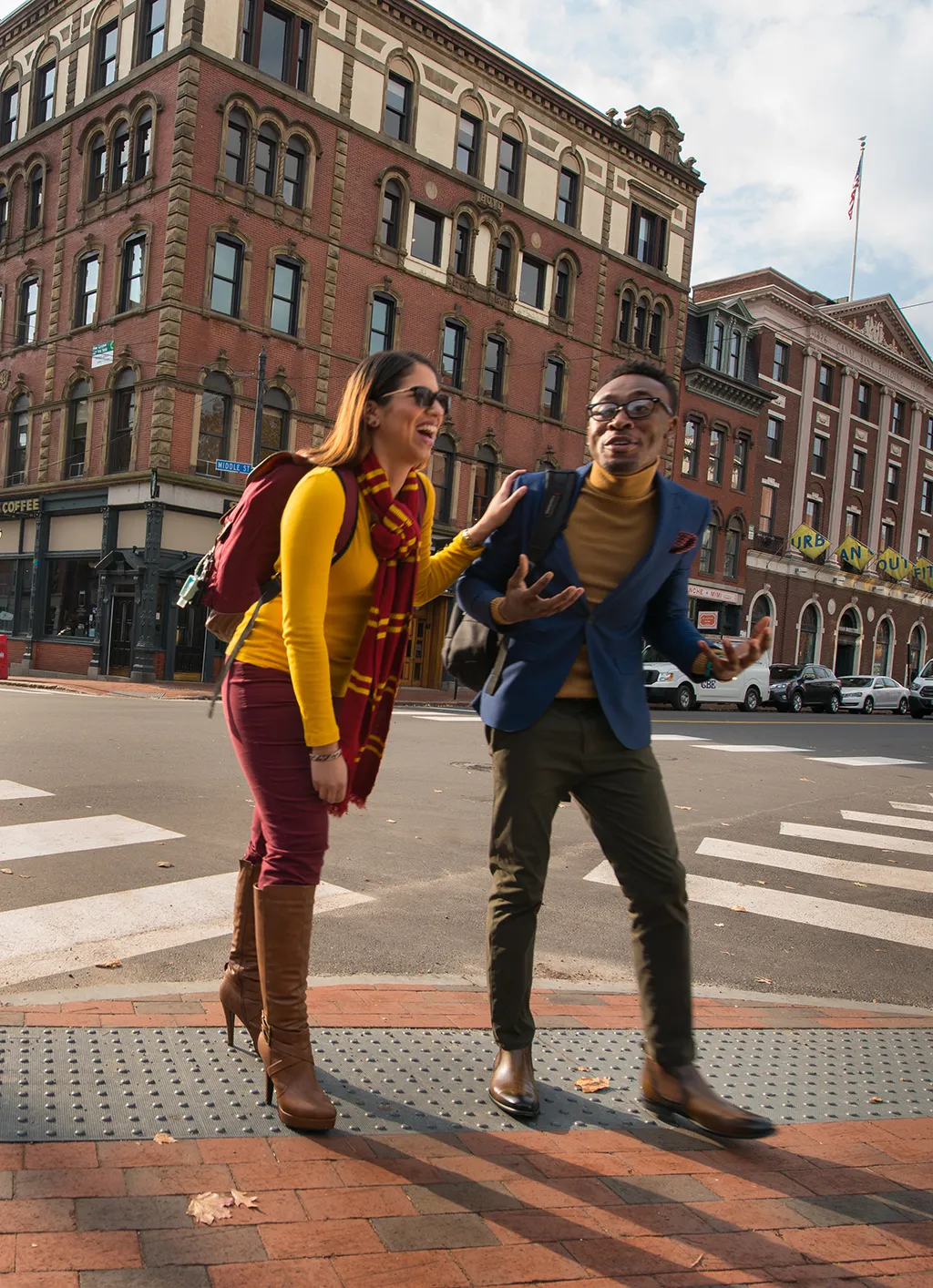 Two students walking across the street with brick buildings in the background