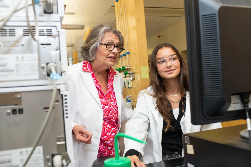 Karen Houseknecht and a student examine research data at a computer screen