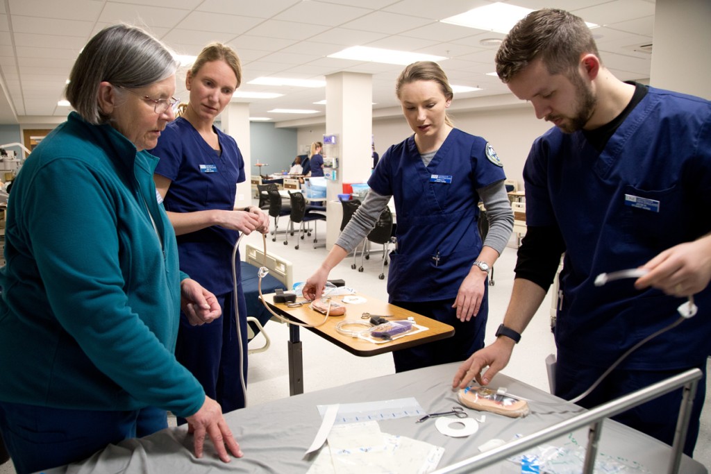 A nursing professor explains hospital tools to three students