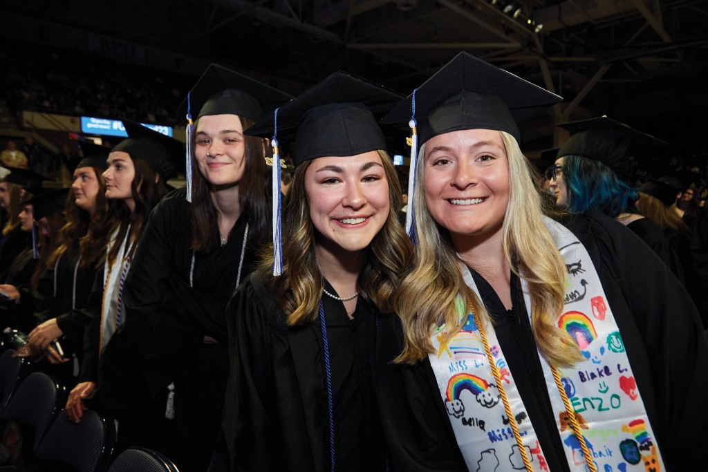 two students smile for the camera at commencement