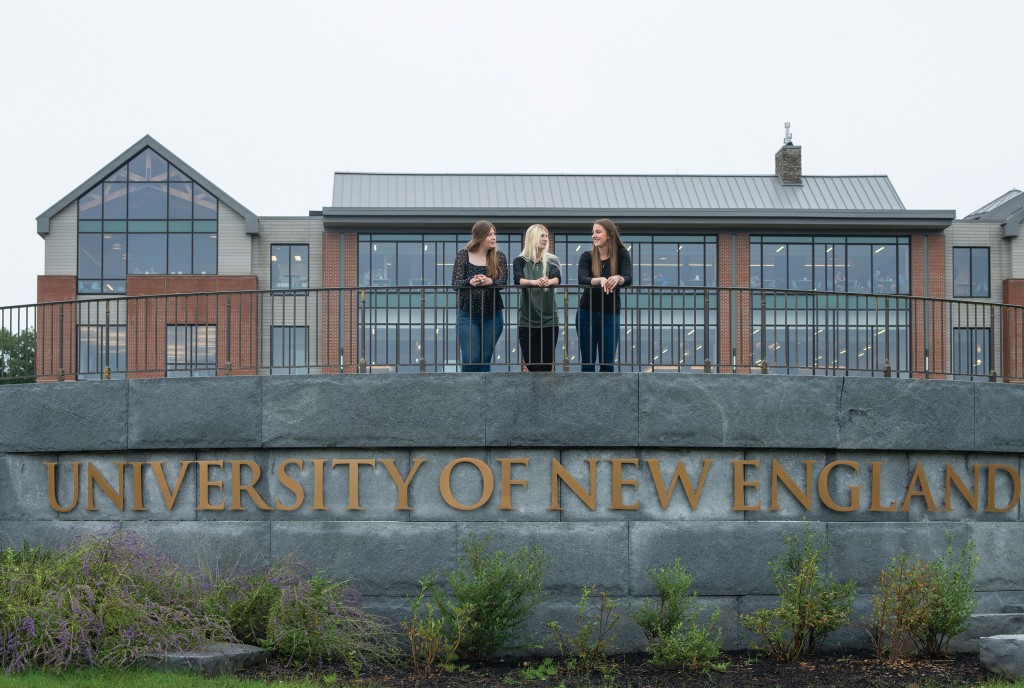 Davis Scholars attending U N E stand on the walkway above the University of New England lettering on the Biddeford Campus