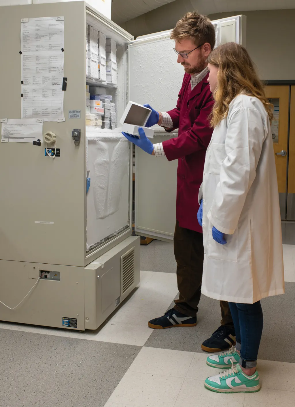 Jayden and Dr. Harrison stand in front of an open lab freezer