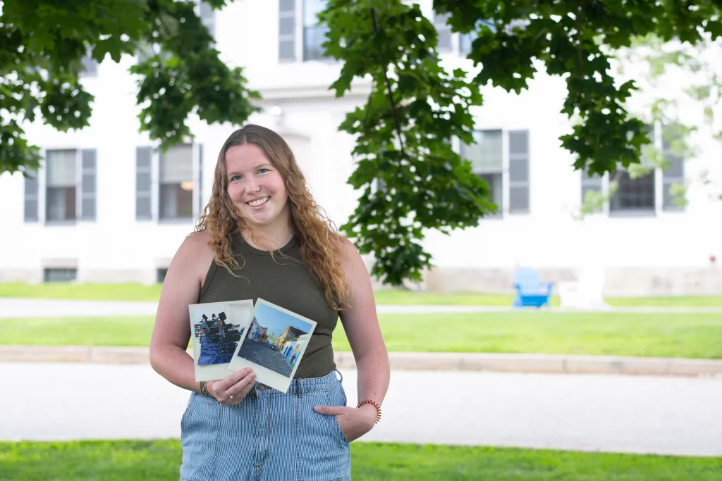 Kiara holds up two large polaroids from her time in Guatemala