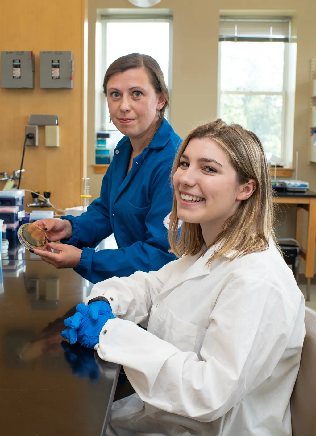 Professor Balog holds up an agar plate while standing next to a student researcher