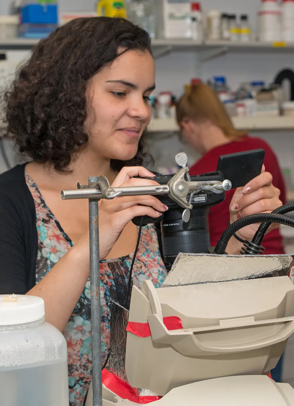 A student using a D S L R camera to take photos of lab equipment