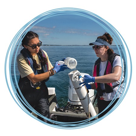 Two marine science students filling a sampling container with ocean water