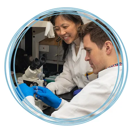 A faculty member assists a research student with setting up a microscope
