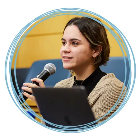 A student holds a microphone while they ask a question at a U N E lecture event