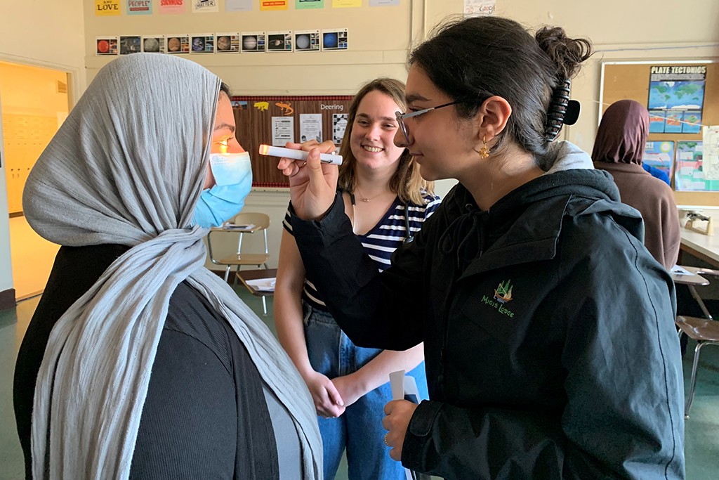  High school student Malak Alobaidi examines UNE student Fajar Alam's eyes during a health assessment exercise