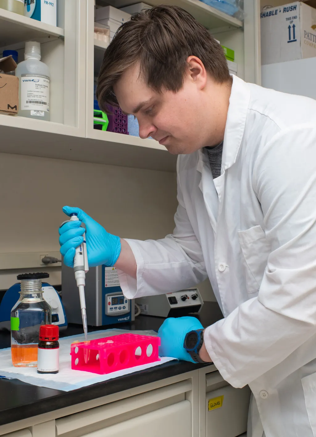 A student pipes a liquid into a container in a research lab
