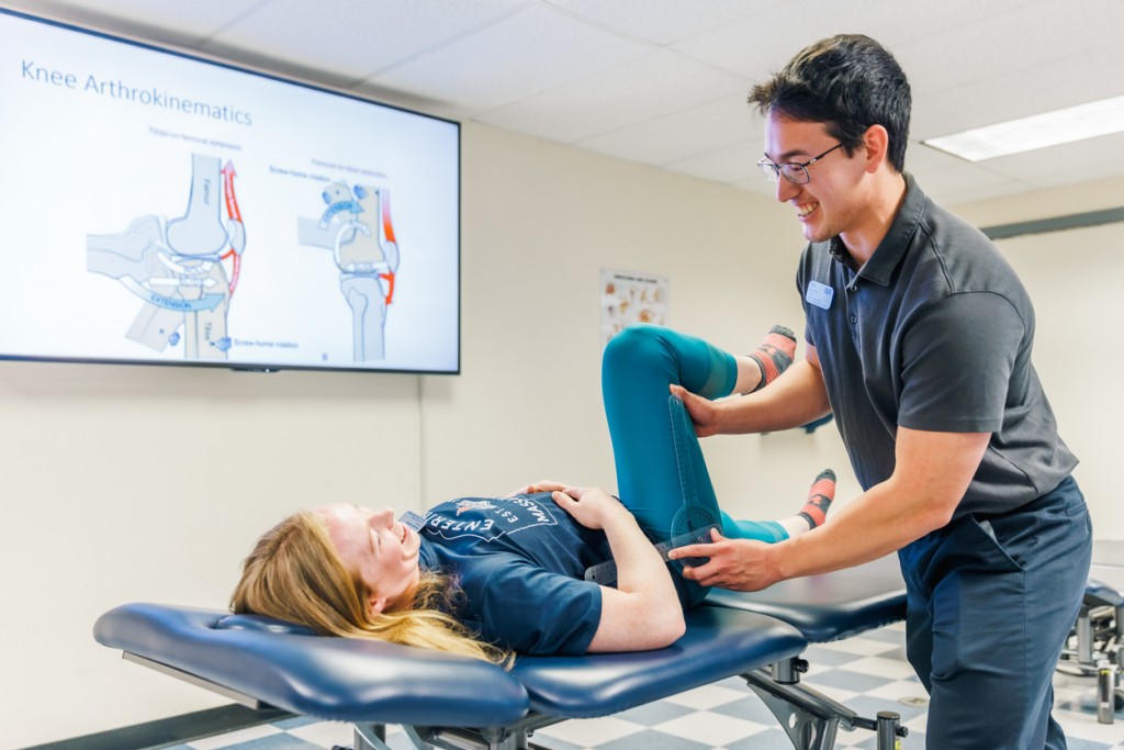 A physical therapy student practices checking a patient's leg mobility