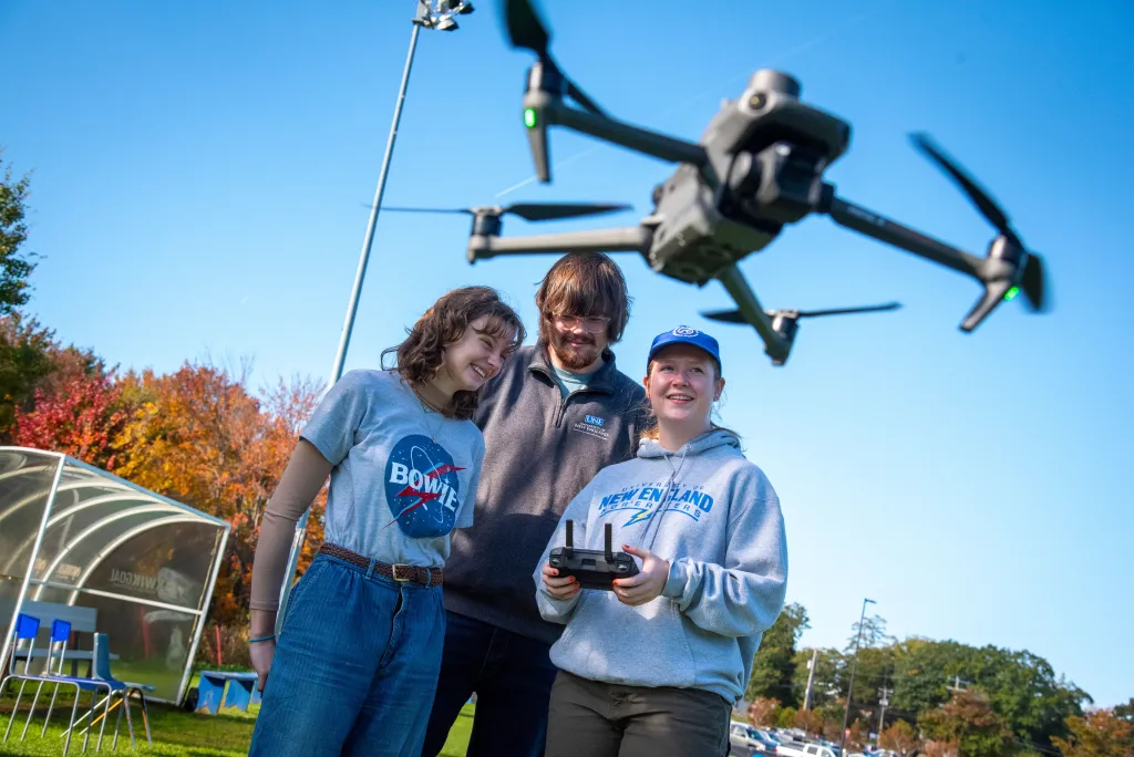 Students huddle over controls to fly a drone