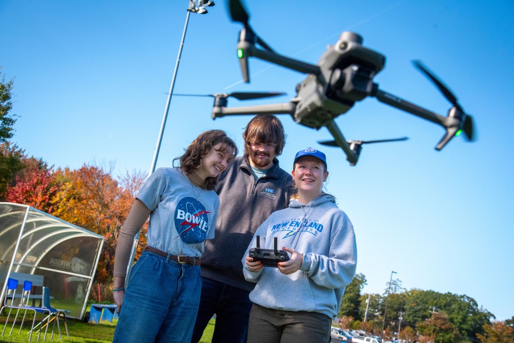 Students huddle over controls to fly a drone 