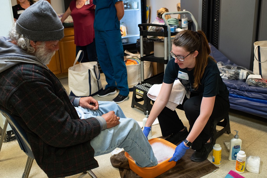 A student washes a man's feet at Milestone Recovery in Portland, ME