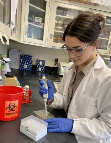 A female students uses a pipette in a lab
