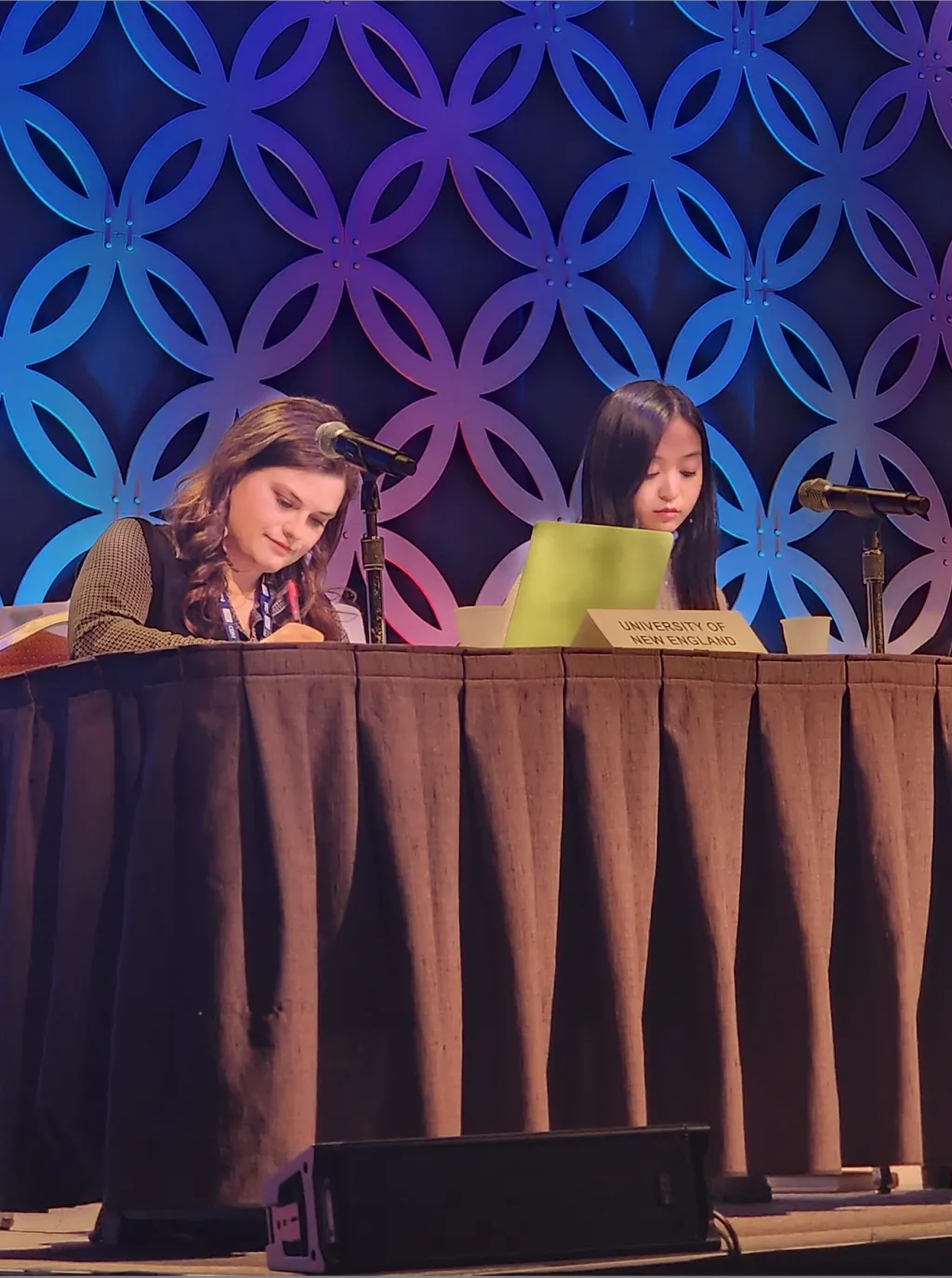 Two female students sit at a debate table