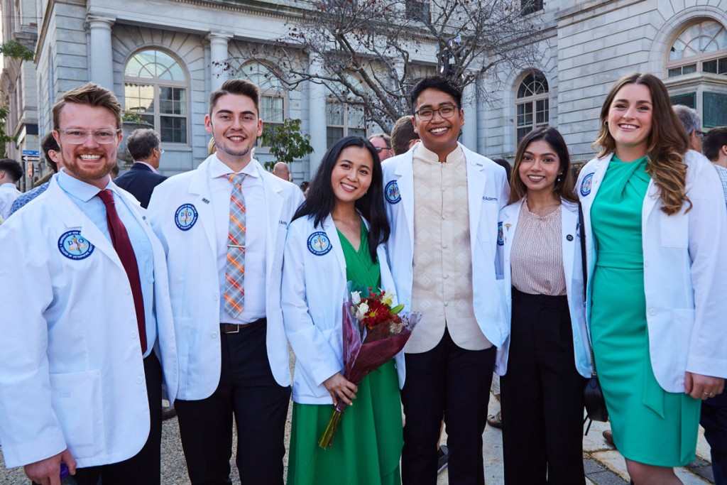 A group of C O M students in their white coats