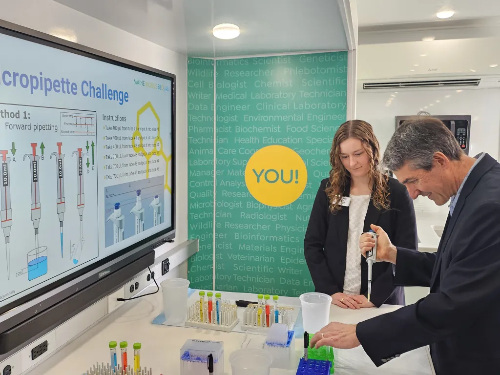 A faculty member uses a pipette in a mobile lab