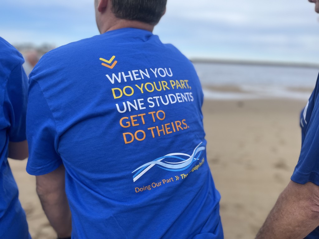 The back of a UNE-branded t-shirt reads, "When you do your part, UNE students get to do theirs."