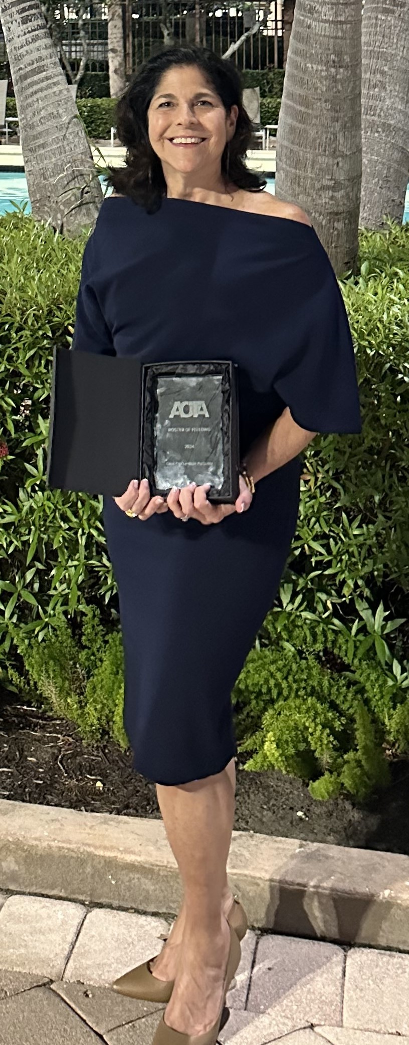 A UNE OT professor poses with a plaque after being inducted into the AOTA Roster of Fellows