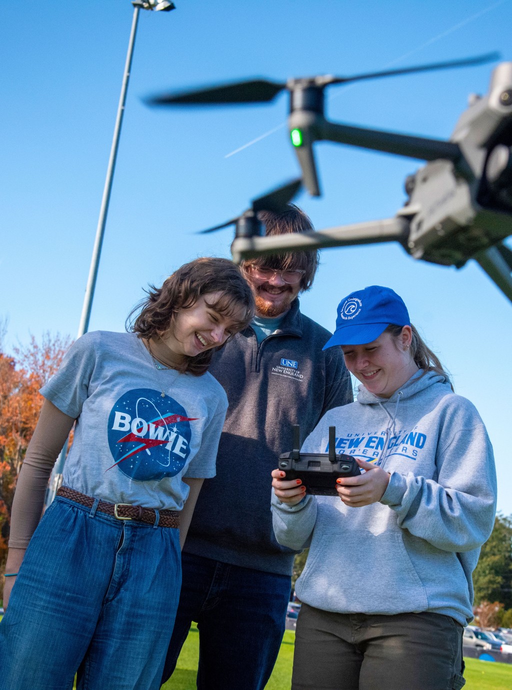 Three UNE students fly a drone