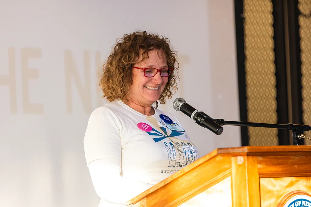 Photo of a woman speaking into a microphone at a podium