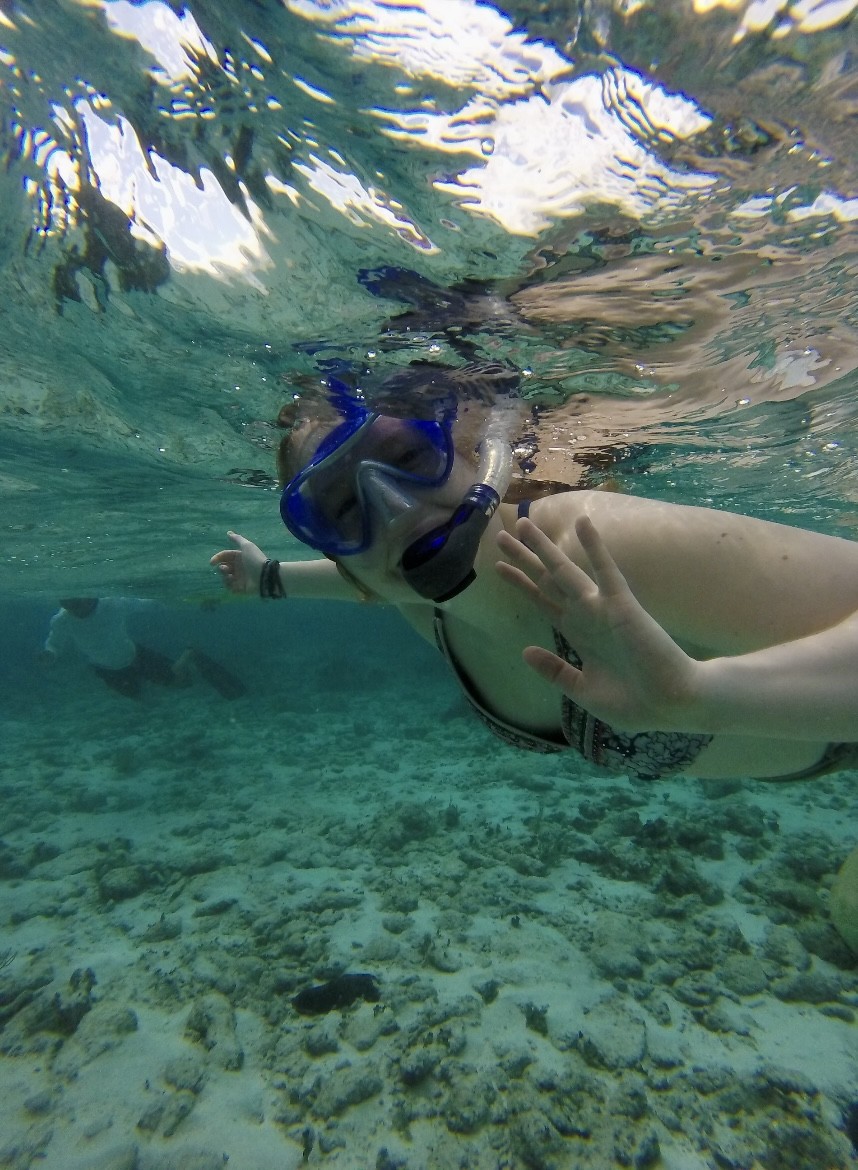 A UNE student waves underwater while SCUBA diving