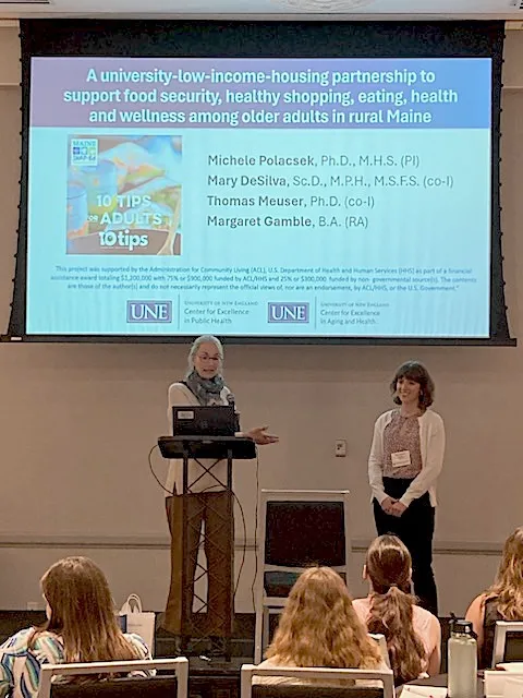 Michele Polacsek and Margaret Gamble stand in front of people presenting research