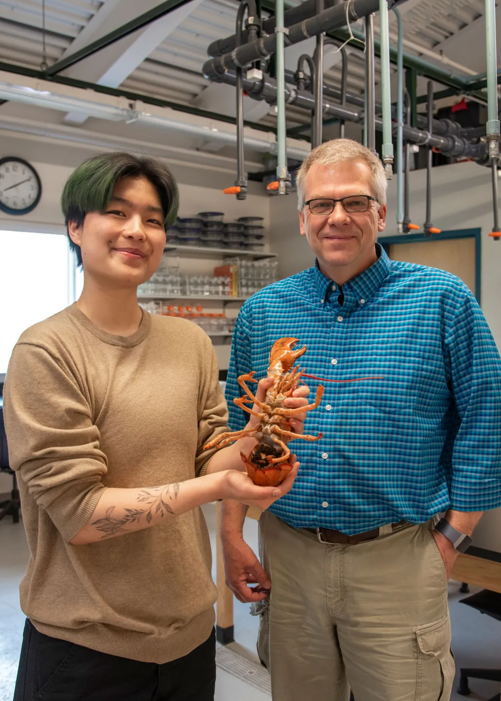 Ruby Motulsky holds an orange lobster and poses with Markus Frederich
