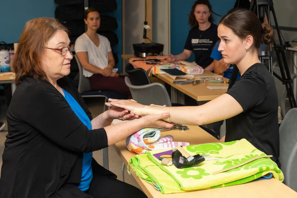 A guest lecturer shows how to put a handmade splint on an O T student